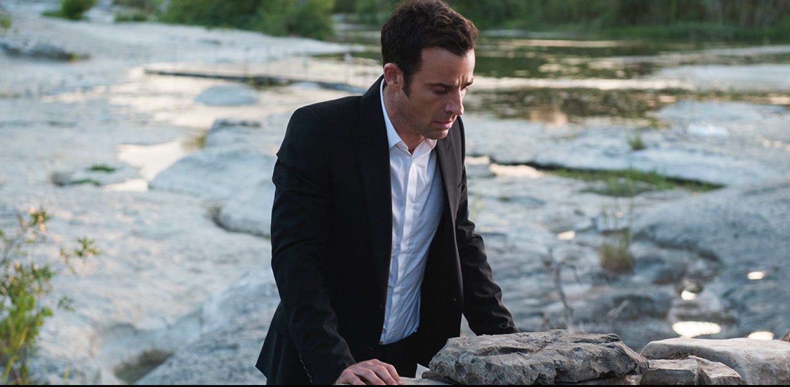 A man with a suit looking down towards a well.